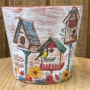 May include: A white ceramic mug with a black handle and the text "But First, Coffee" in a black, handwritten-style font. The mug is on a white surface.