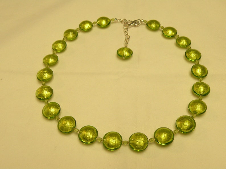 May include: A green glass necklace with round beads. The beads have a metallic sheen and are strung on a silver chain.
