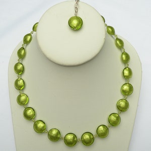 May include: A green glass bead necklace with a matching pendant. The beads are round and have a metallic sheen.