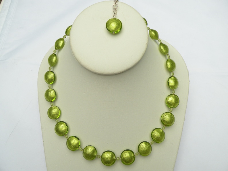 May include: A green glass bead necklace with a matching pendant. The beads are round and have a metallic sheen.