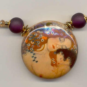 Puede incluir: Collar con un colgante redondo que representa a dos mujeres en tonos c&aacute;lidos. El colgante se complementa con cuentas moradas y una hebra de peque&ntilde;as cuentas doradas brillantes. El collar es una joya art&iacute;stica.