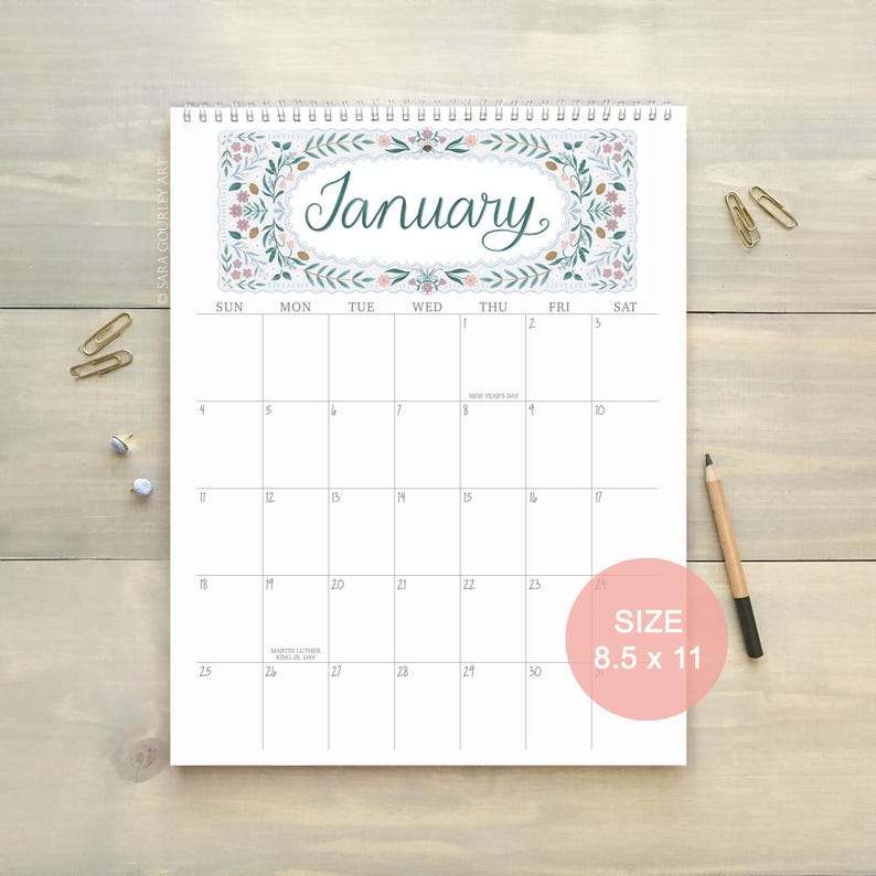 Pu&ograve; includere: Un calendario da parete a spirale aperto su gennaio. La parte superiore presenta un motivo floreale con la parola "January". Il calendario misura 21,6 x 27,9 cm, con i giorni della settimana in alto e le date nella griglia.