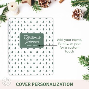 Custom Christmas Planner cover close-up with arrow pointing to custom name line for family name or year. Features green Christmas tree pattern on white background and white spiral binding. Holiday organizer is beside pine branches with pinecones, and ribbon. Custom holiday planner notebook for organizing Christmas gifts, budget, and holiday plans.