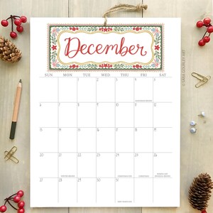 Pu&ograve; includere: Un calendario di dicembre con un bordo floreale decorativo e la parola "Dicembre" in corsivo rosso. Il calendario include date e festivit&agrave; come la vigilia di Natale e Capodanno. Il calendario &egrave; appeso con uno spago.