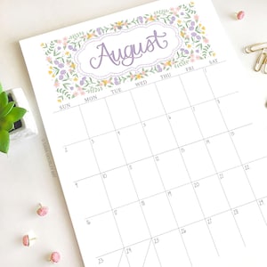 Pu&ograve; includere: Una pagina del calendario di agosto a tema floreale. La parola "August" &egrave; scritta in un carattere viola decorativo, incorniciata da un bordo floreale con fiori rosa, gialli e viola. La griglia del calendario &egrave; grigia.