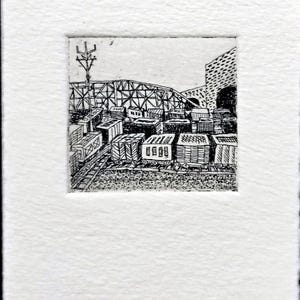 May include: A black and white ink drawing on textured paper depicting a train yard with multiple boxcars on tracks. In the background, a large metal truss bridge spans the scene, with a utility pole on the left and a brick wall structure on the right.