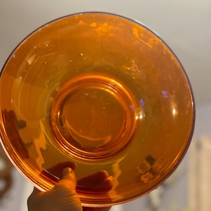 May include: A large, round, orange glass bowl with a reflective surface.