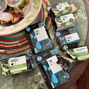 May include: A collection of HP ink cartridges including models 932XL, 932, 933, 950XL, 45, and 78. The packaging features blue butterfly graphics on black backgrounds, white labels with black text, and color-coded indicators for black and tri-color ink.