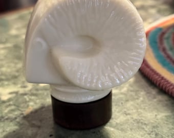 May include: White ceramic bottle stopper shaped like a ram's head with a brown wooden base.