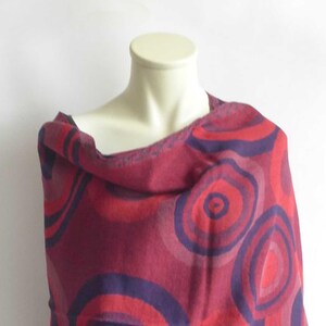Könnte beinhalten: Ein rot-violetter Schal mit kreisförmigem Muster. Der Schal ist aus einem weichen, warmen Material gefertigt und perfekt, um jedem Outfit einen Farbtupfer zu verleihen.