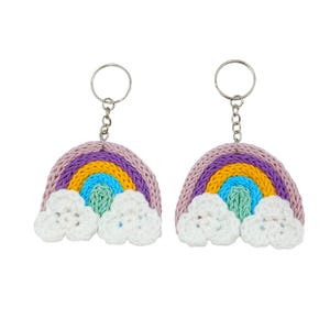 May include: Two rainbow keyrings. Each keyring features a crocheted rainbow with purple, yellow, blue, and green arches, and white cloud accents. The keyrings have silver-coloured key rings attached.