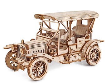 Puede incluir: Maqueta de madera de un coche antiguo con detalles intrincados. El coche tiene techo, asientos abiertos y ruedas de radios. El modelo está hecho de madera clara y parece ser un rompecabezas o un kit de construcción.