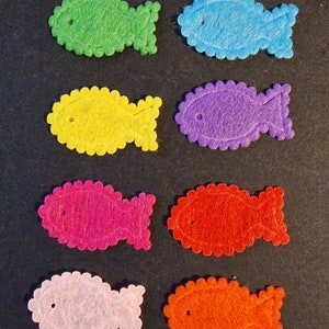 May include: Seven felt fish shapes in various colors: green, blue, yellow, purple, pink, light pink, and orange. The fish are all the same size and shape, with a scalloped edge.