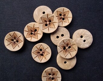 May include: A collection of 10 wooden buttons with a floral design. The buttons are light brown with a darker brown floral pattern.