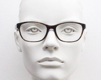 Puede incluir: Una cabeza de maniquí blanca con gafas de pasta de carey con montura negra.
