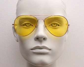 Lunettes de soleil aviateur jaunes en forme de larme. Monture classique en métal doré avec verres jaunes. Blouson aviateur pour homme des années 70. NSA