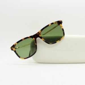 May include: Tortoiseshell sunglasses with green lenses and a white case that says "MARC JACOBS".