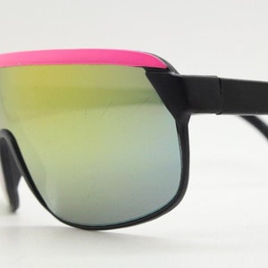 Puede incluir: Gafas de sol negras con ribete rosa y lentes espejadas.