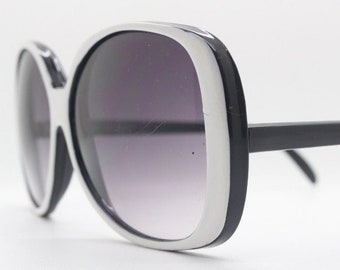 May include: Oversized sunglasses with a rounded frame and dark lenses, in black and white.