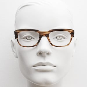 May include: A white mannequin head wearing brown and tan striped eyeglasses.
