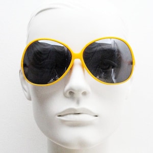 70s vintage womens big round sunglasses. Bright orange oversized bug eye frame with black lenses and undulating arms. 80s. NOS