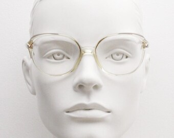 May include: Clear plastic framed glasses with a cat eye shape. The glasses are on a white mannequin head.