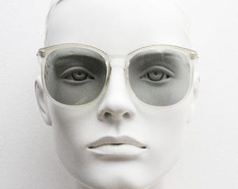 Gafas de sol vintage de los años 80 para mujer, de gran tamaño, fabricadas en Francia por Polaroid. Montura blanca transparente con lentes grises de un tono claro y singularmente atmosféricas.