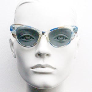 Puede incluir: Un par de gafas de sol de ojo de gato azules y blancas con montura blanca y lentes azules.