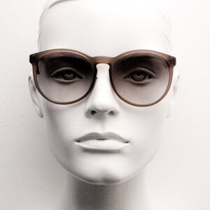 80s vintage women's round sunglasses made in Italy. Transparent frosted grey frame with smoky lens gradient. Unused NOS