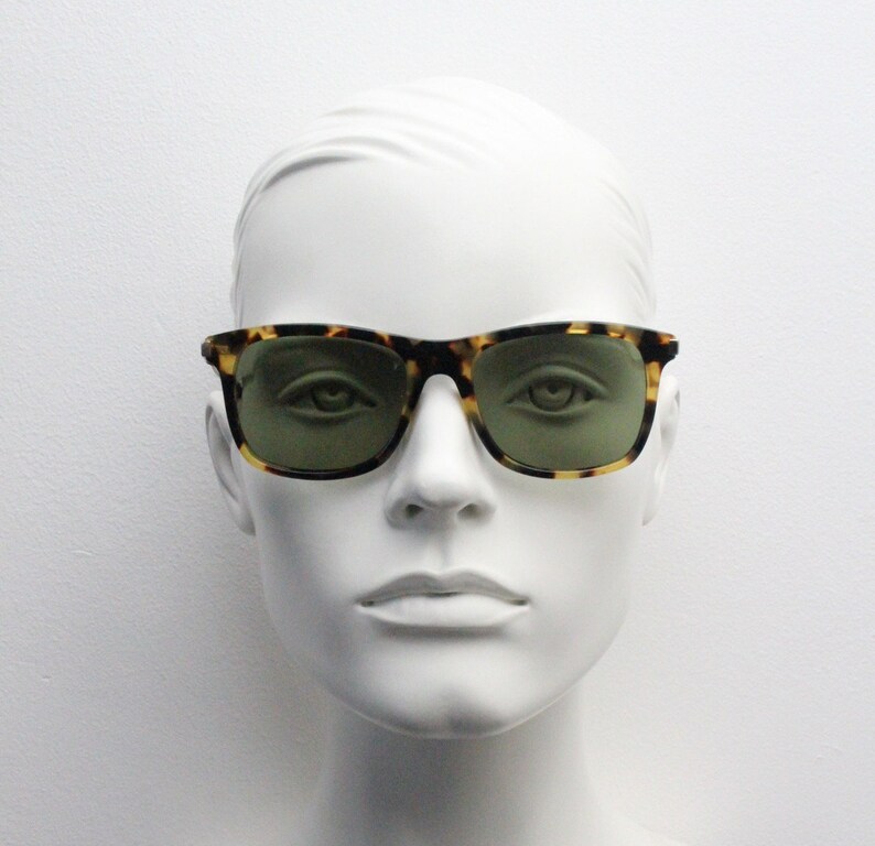 May include: A mannequin wearing tortoiseshell sunglasses with green lenses.
