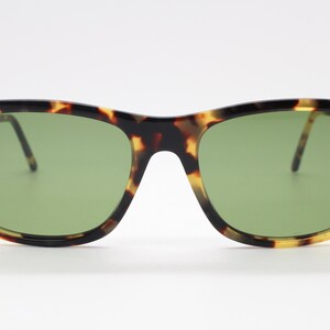 May include: Tortoiseshell sunglasses with green lenses. The sunglasses have a gold metal frame.