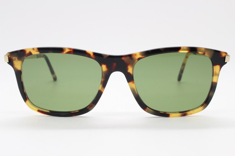 May include: Tortoiseshell sunglasses with green lenses. The sunglasses have a gold metal frame.