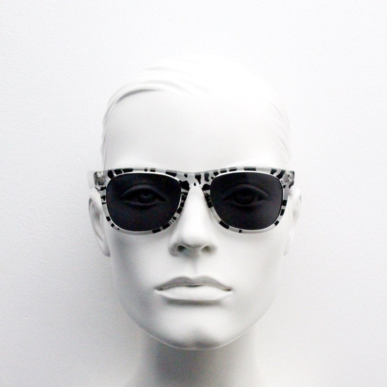May include: A white mannequin head wearing black and white patterned sunglasses with black lenses.