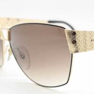 Christian Dior 80s vintage sunglasses made in Austria. Dynamic oversized gold metal cat eye frame with graduated smoky lenses
