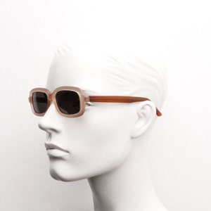 May include: A pair of brown square-shaped sunglasses with a brown frame. The sunglasses are on a mannequin's face.