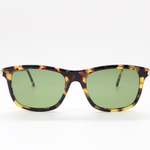 May include: Tortoiseshell sunglasses with green lenses. The sunglasses have a square frame.
