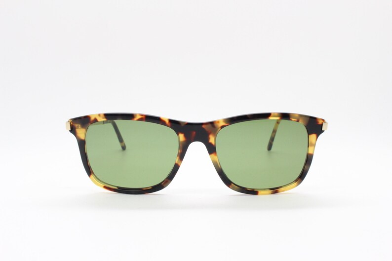 May include: Tortoiseshell sunglasses with green lenses. The sunglasses have a square frame.