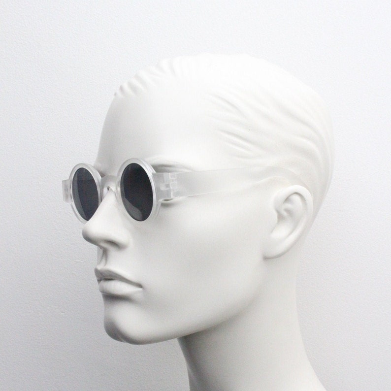 May include: Clear plastic round frame sunglasses with dark lenses.