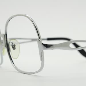 May include: Silver-toned metal eyeglasses with a unique, open-work design on the temples.
