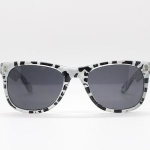 May include: Black and white patterned sunglasses with dark gray lenses.