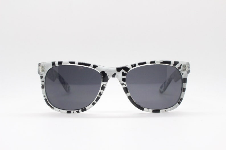 May include: Black and white patterned sunglasses with dark gray lenses.