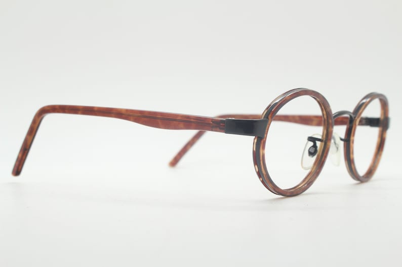 May include: Brown tortoiseshell eyeglasses with round black metal frames.