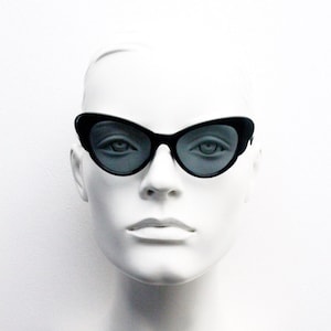 Puede incluir: Una cabeza de maniquí blanca con gafas de sol negras de ojo de gato con lentes grises.