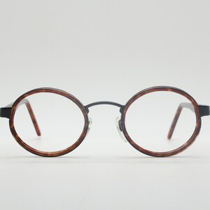 May include: Round tortoiseshell eyeglasses with black metal frames.