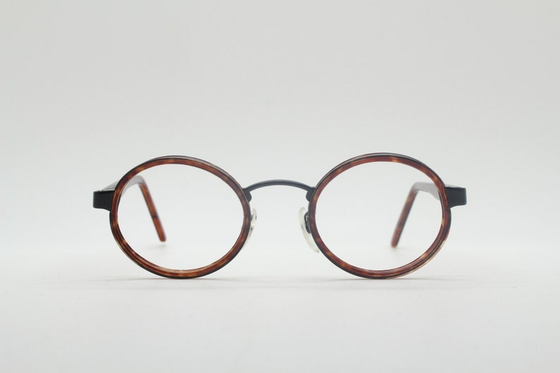 May include: Round tortoiseshell eyeglasses with black metal frames.