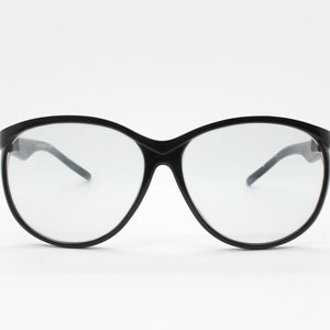 80-tals vintage överdimensionerade cat eye-solglasögon. Svarta glansiga cateye-bågar med extremt ljusa rökfärgade glaslinser. Dammodell 70-tal. Oanvända NOS