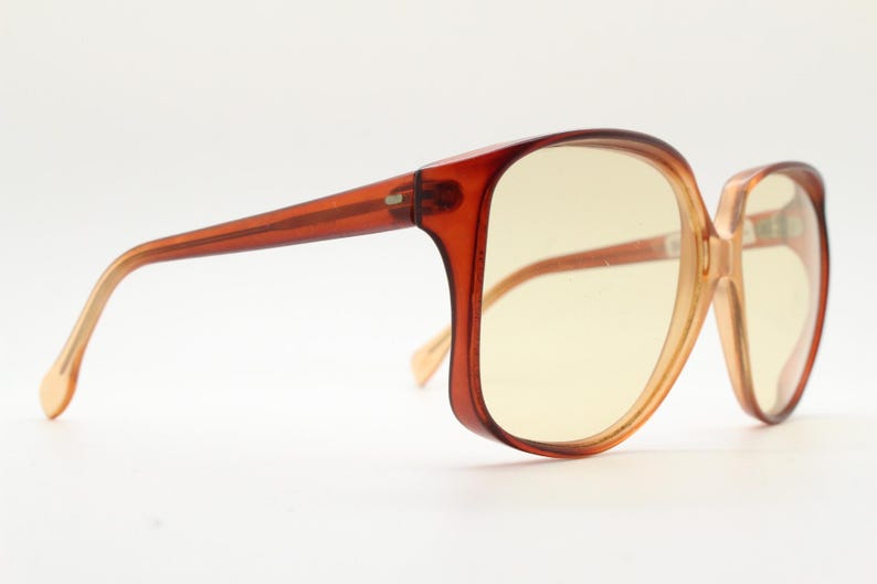 Op de afbeelding: Vintage oversized zonnebril met een bruin verloop montuur en geel getinte glazen. De monturen hebben een vierkante vorm met een licht cat-eye design. De pootjes zijn een lichtere bruintint.