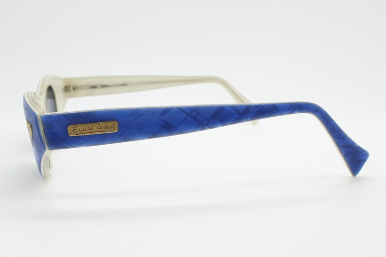 Op de afbeelding: Witte zonnebril met blauw patroon en een gouden logo met de tekst "Emilio Cavalli".
