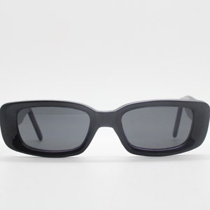 May include: Black rectangular sunglasses with a dark gray lens.