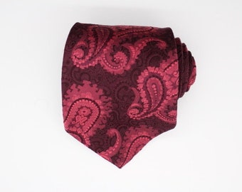 May include: A burgundy paisley patterned tie. The tie is made of a silky material and has a classic design.